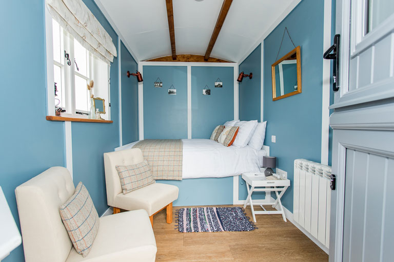 Photo of Jill Hoot's blue interior, showing the double-bed and easy chairs